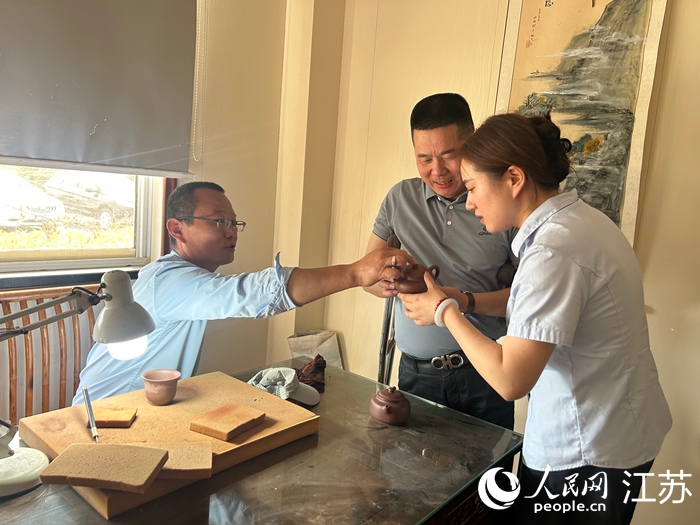 马伟忠（中）与紫砂工艺师（左）交流作品设计思路。人民网 王丹丹摄